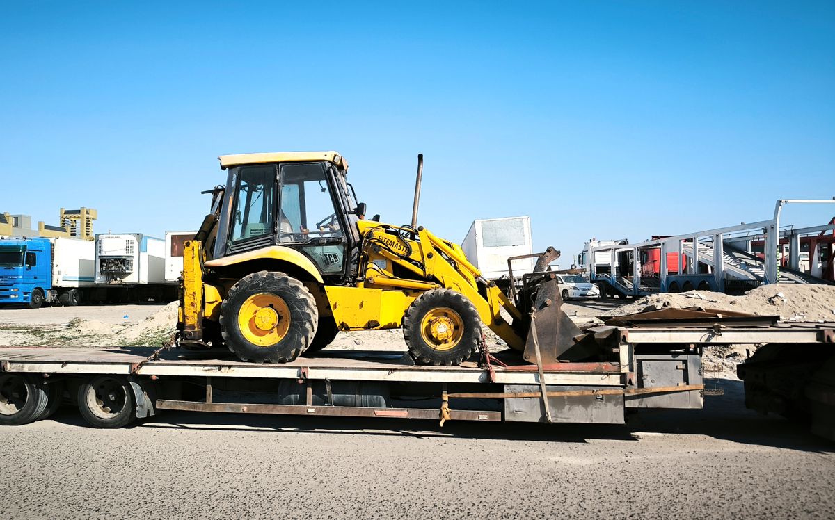 Maquinaria amarilla sobre un remolque de transporte industrial